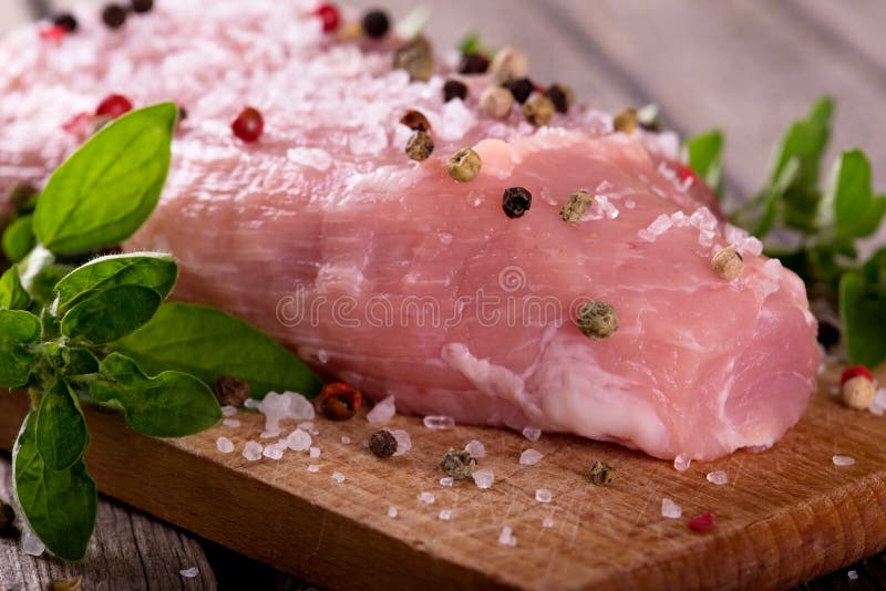 Detail of raw pork meat with salt and color pepper on chopping board