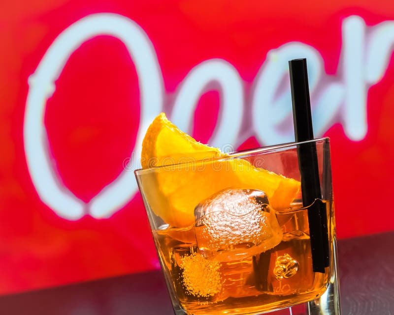 Detail van glas van aperolcocktail van het spritzaperitief met oranje plakken en ijsblokjes op barlijst, de achtergrond van de di stock afbeelding Detail van glas van aperolcocktail van het spritzaperitief met oranje plakken en ijsblokjes op barlijst, de achtergrond van de di stock afbeelding