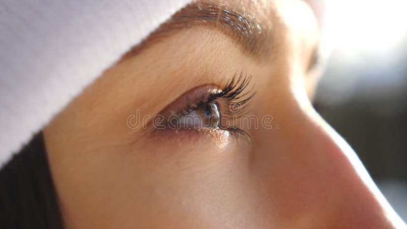 Detail view of woman brown eyes looking around. Attractive brown-eyed girl blinking and admiring beautiful winter views