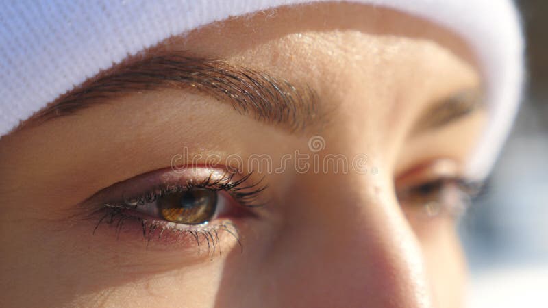 Detail view of woman brown eyes looking around. Attractive girl standing in winter forest and admiring beautiful view