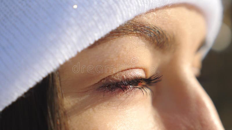 Detail view of woman face with beautiful brown eyes. Attractive girl standing in winter forest and looking around. Slow