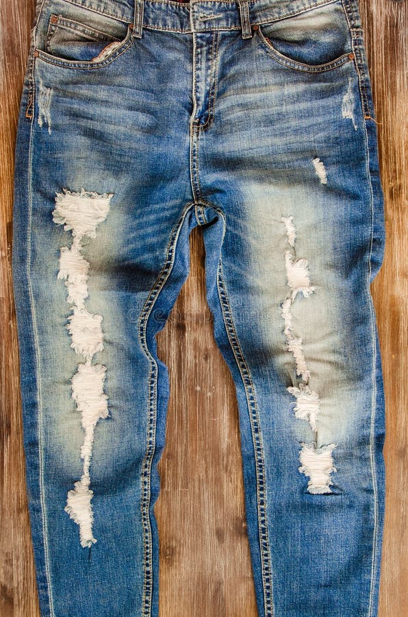 Detail of vintage weathered jeans on wood texture stock photos