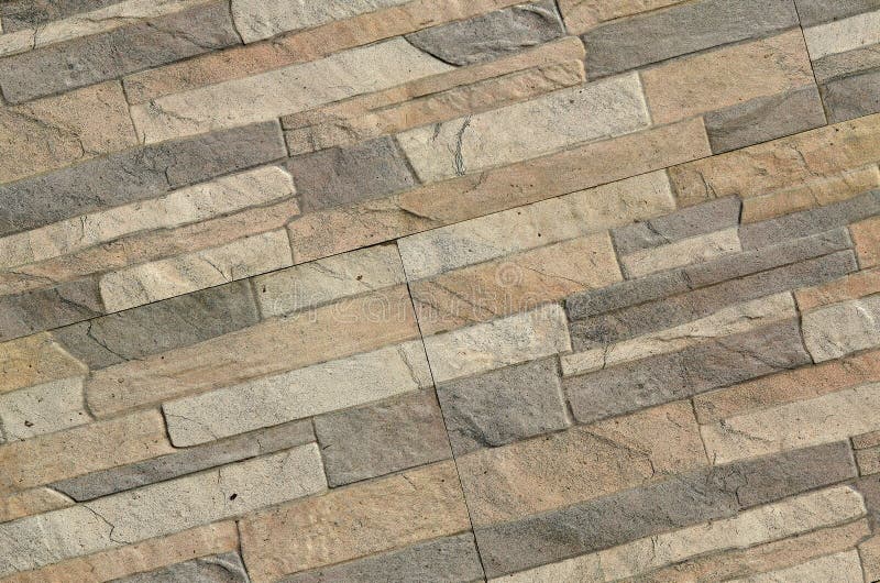 Detail of a wall of a long gray and brown brick. The facade of the building, built of natural stone. Background textur