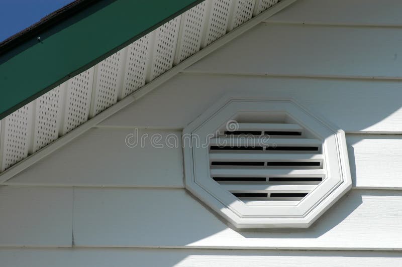 Detail of white aluminum siding, white vinyl vent, white soffit and dark green fascia