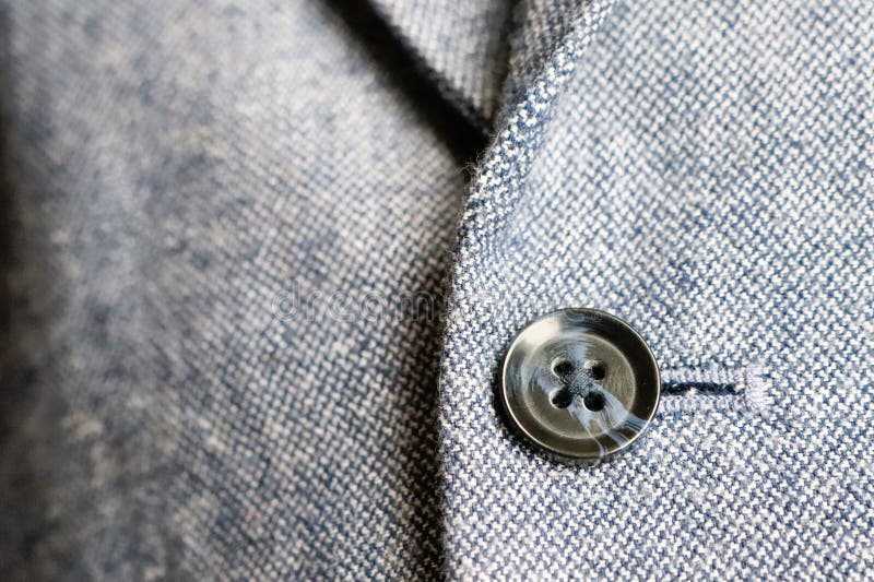 A detailed closeup showing a stylish suit jacket button and the unique texture of fabric royalty free stock photo