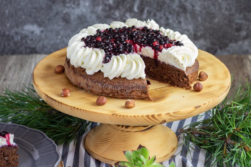 Detailed view on a forest chocolate hazelnut cake with wild strawberries, blueberries, raspberries and blackberries garnished with whipped cream