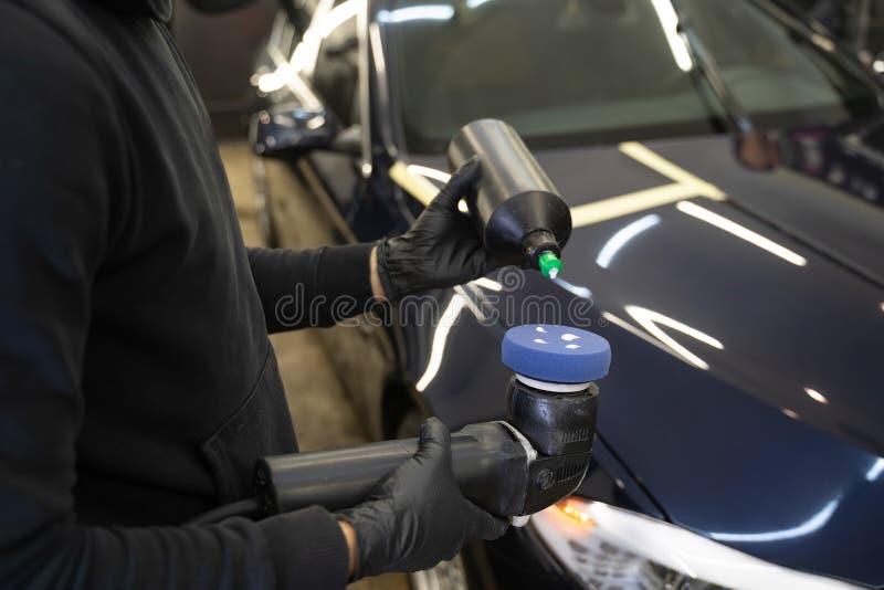 Detailing master applies car polish paste to the polisher. Vehicle paintwork polishing concept.