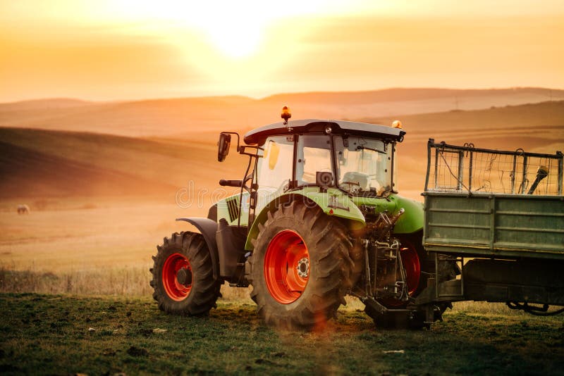 Details van tractor, landbouwer die op de gebieden met tractor aan een zonsondergangachtergrond werken De details van de landbouw