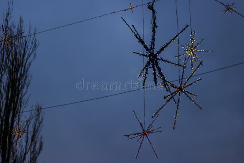 Details of street Christmas lights, snowflakes in the blue sky and part of a Christmas tree. Details of street Christmas lights, snowflakes in the blue sky and part of a Christmas tree.