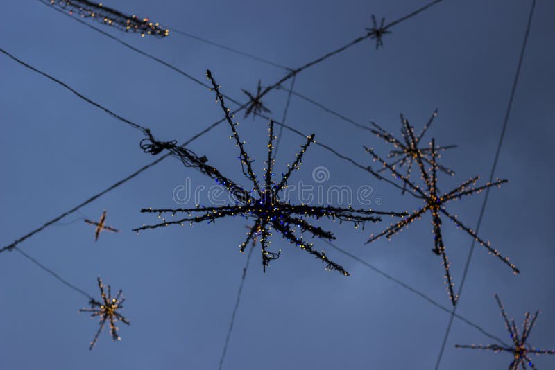 Details of street Christmas lights, snowflakes in the blue sky. Christmas lights. Details of street Christmas lights, snowflakes in the blue sky. Christmas lights