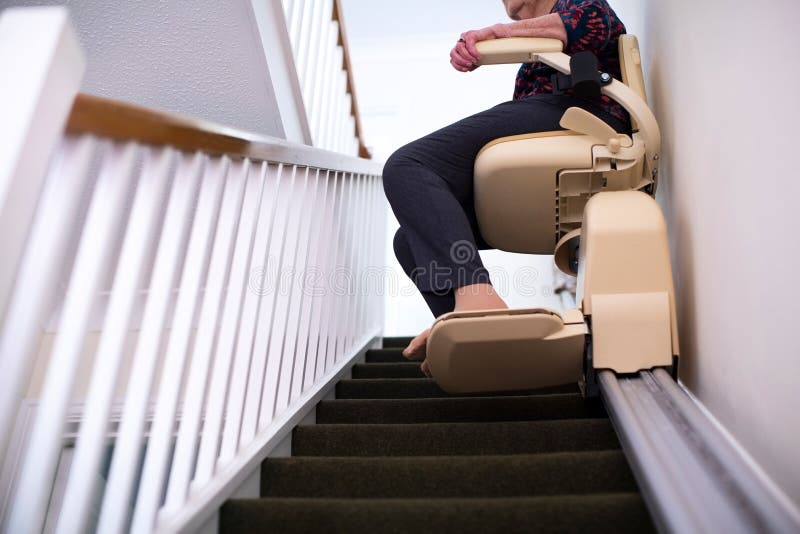 Detalhe de mulher superior que senta-se no elevador da escada em casa para ajudar a mobilidade