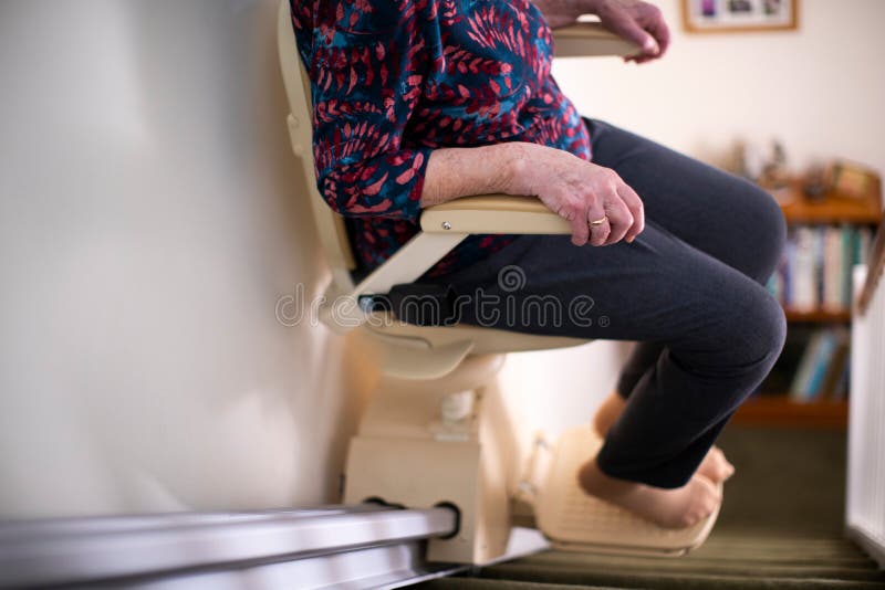 Detalhe de mulher superior que senta-se no elevador da escada em casa para ajudar a mobilidade imagem de stock Detalhe de mulher superior que senta-se no elevador da escada em casa para ajudar a mobilidade imagem de stock