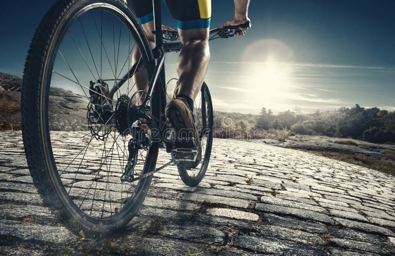 Detalhe de pés do homem do ciclista que montam o Mountain bike na fuga exterior na estrada secundária