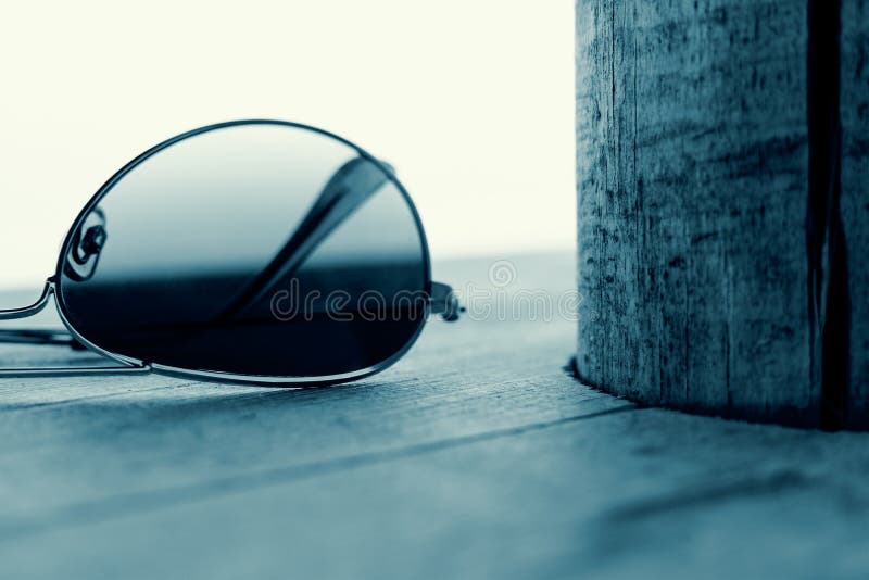 Detalhe espelhado dos óculos de sol no fundo de madeira Conceito da forma em ciano imagem de stock royalty free Detalhe espelhado dos óculos de sol no fundo de madeira Conceito da forma em ciano imagem de stock royalty free