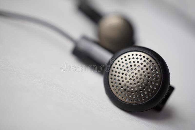 Detalhe macro de uma prata e de uns fones de ouvido perfurados pretos (orelha-botões) com cabos imagens de stock royalty free Detalhe macro de uma prata e de uns fones de ouvido perfurados pretos (orelha-botões) com cabos imagens de stock royalty free