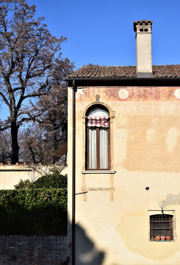Detaljer om ett historiskt hus som lyser av solen i den blå himlen med ett stort och vackert träd till vänster royaltyfria bilder Detaljer om ett historiskt hus som lyser av solen i den blå himlen med ett stort och vackert träd till vänster royaltyfria bilder