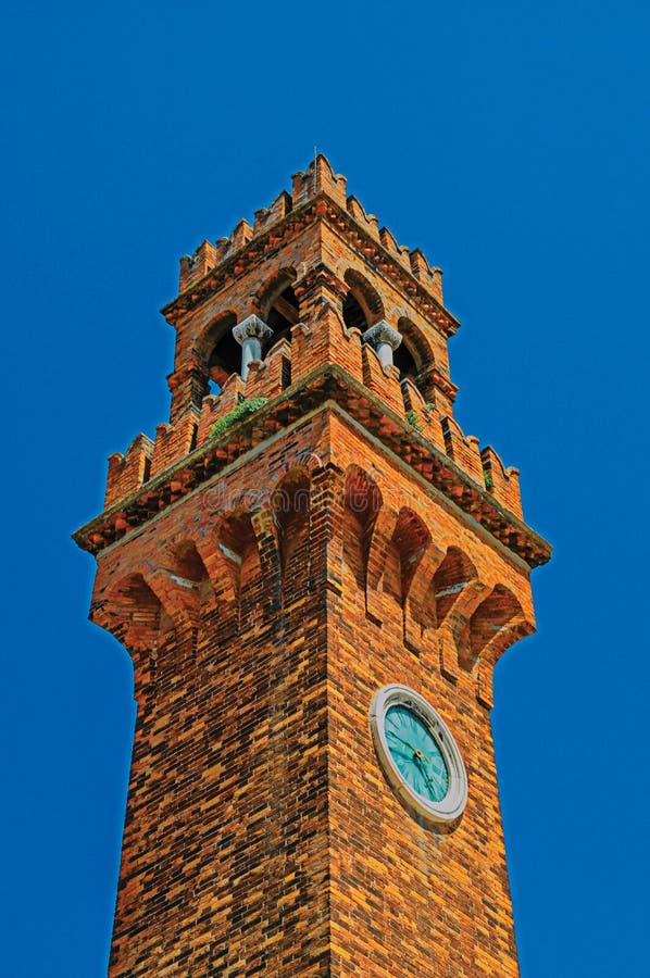 Detalle de la torre de reloj hecho de ladrillos con el cielo azul soleado en Murano foto de archivo Detalle de la torre de reloj hecho de ladrillos con el cielo azul soleado en Murano foto de archivo