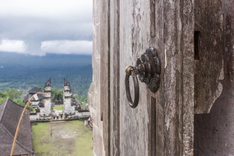 Horizontal photo of detail of an old door knob in Pura Penataran Agung with Gates of Heaven in the distance, on the way up to Pura Luhur Lempuyang temple. Horizontal photo of detail of an old door knob in Pura Penataran Agung with Gates of Heaven in the distance, on the way up to Pura Luhur Lempuyang temple