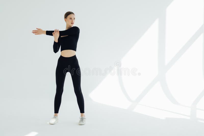 Determinada mulher desportiva forte e saudável que estica os braços aquecendo-os para o treino no ginásio, olhando para o lado