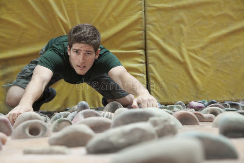 Determined young man climbing up a climbing wall in an indoor climbing gym, directly above