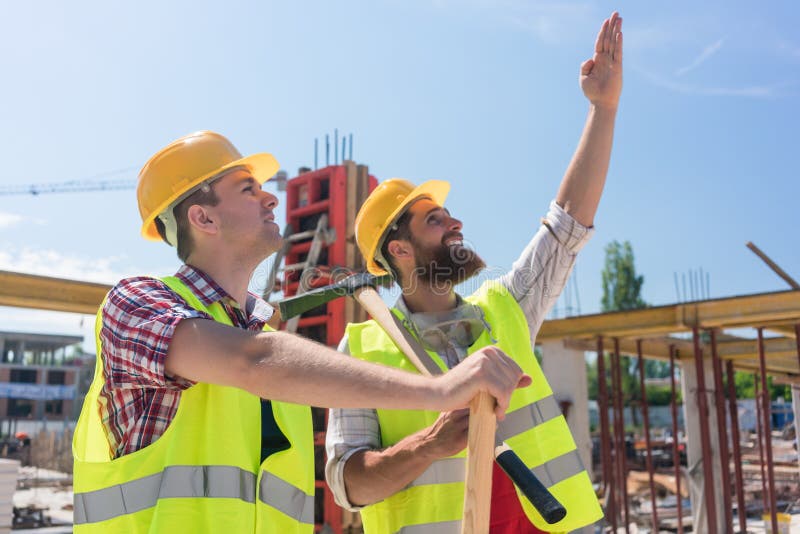 Determined young worker pointing up while imagining the height of a building stock photography