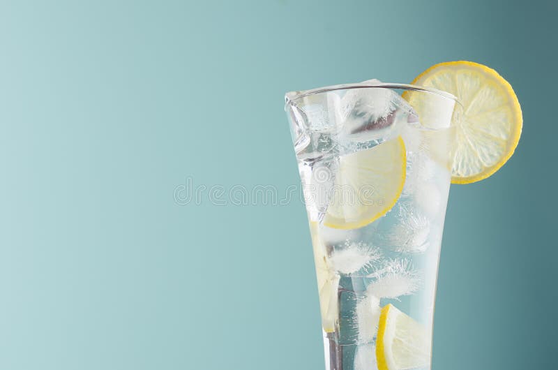 Detox citrus drink with lemon slices, ice cubes, sparkling water in misted glass in modern mint color background, closeup, edge. stock image Detox citrus drink with lemon slices, ice cubes, sparkling water in misted glass in modern mint color background, closeup, edge. stock image