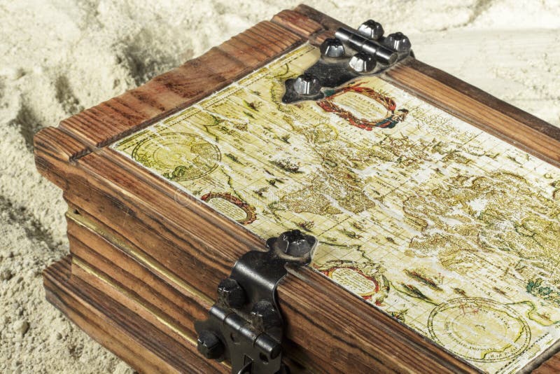 Dettaglio del petto di legno con un portolan sulla sua copertura, sulla sabbia della spiaggia immagini stock libere da diritti Dettaglio del petto di legno con un portolan sulla sua copertura, sulla sabbia della spiaggia immagini stock libere da diritti