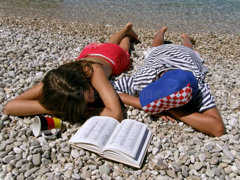 Deutschland-Mädchen und Kroat-Junge, der auf Steinstrand liegt lizenzfreies stockbild Deutschland-Mädchen und Kroat-Junge, der auf Steinstrand liegt lizenzfreies stockbild