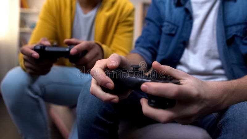 Deux adolescents multiethniques jouant à des jeux d'ordinateur à la maison, mains en l'air