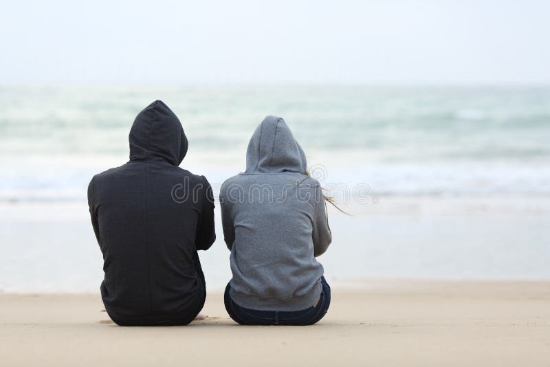 Deux adolescents tristes s'asseyant sur la plage