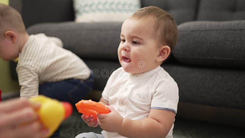 Deux adorables bambins jouant avec des jouets assis par terre à la maison