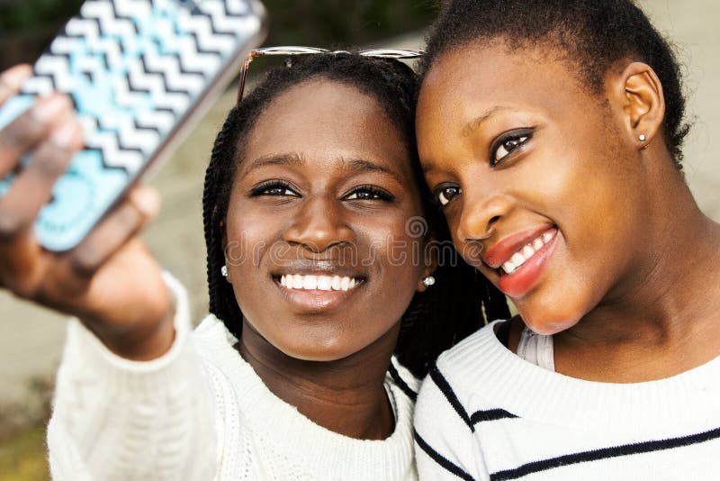 Deux ados africains prenant le selfie avec le téléphone intelligent image libre de droits Deux ados africains prenant le selfie avec le téléphone intelligent image libre de droits