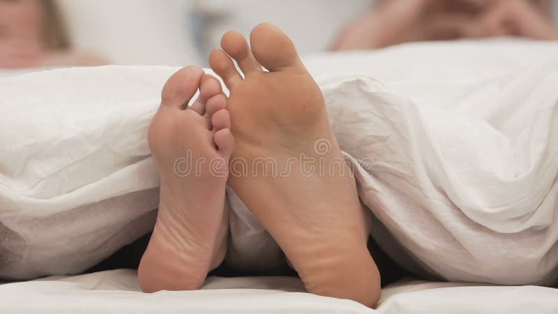 Deux amants dans le lit flirtant par des pieds, romance de relaxation, unité douce