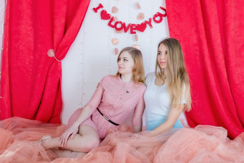 Deux amies aux cheveux longs mignonnes dans des robes s'asseyent et caressent encore photo libre de droits