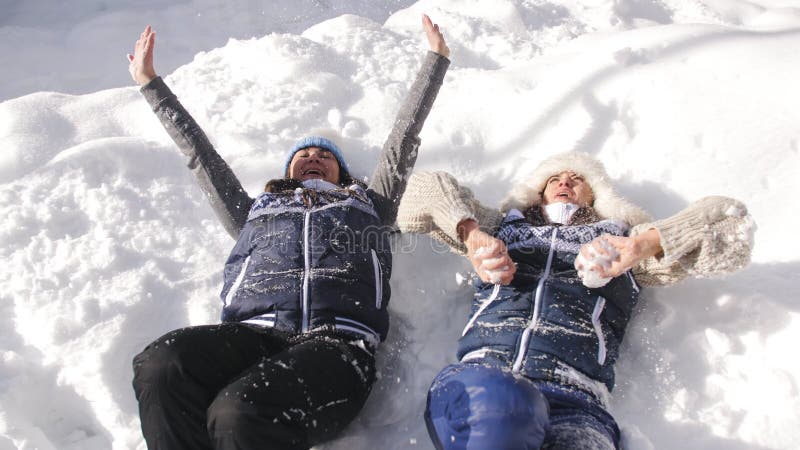 Deux amies de filles dupant autour dans la neige, ayant l'amusement jetant la neige dans le ciel et appréciant en l'air le matin clips vidéos