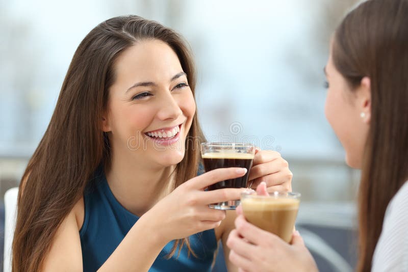 Portrait of two women friends talking holding coffee cups in a restaurant. Portrait of two women friends talking holding coffee cups in a restaurant