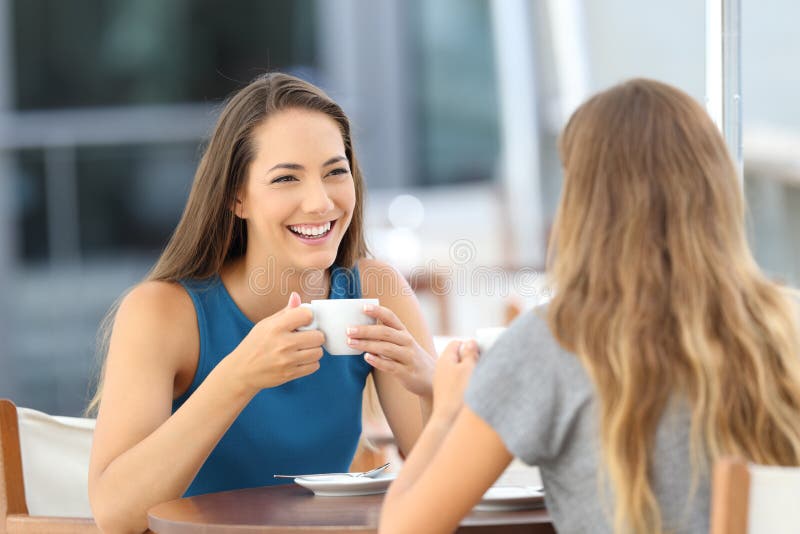 Two happy friends having a casual conversation sitting in a bar terrace. Two happy friends having a casual conversation sitting in a bar terrace