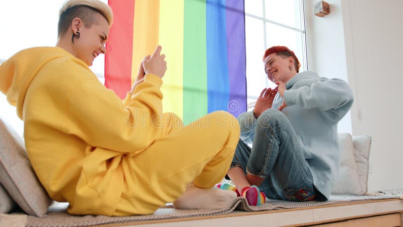 Deux amis se relaxent avec un drapeau de la fierté lgbt arc-en-ciel en arrière-plan banque de vidéos