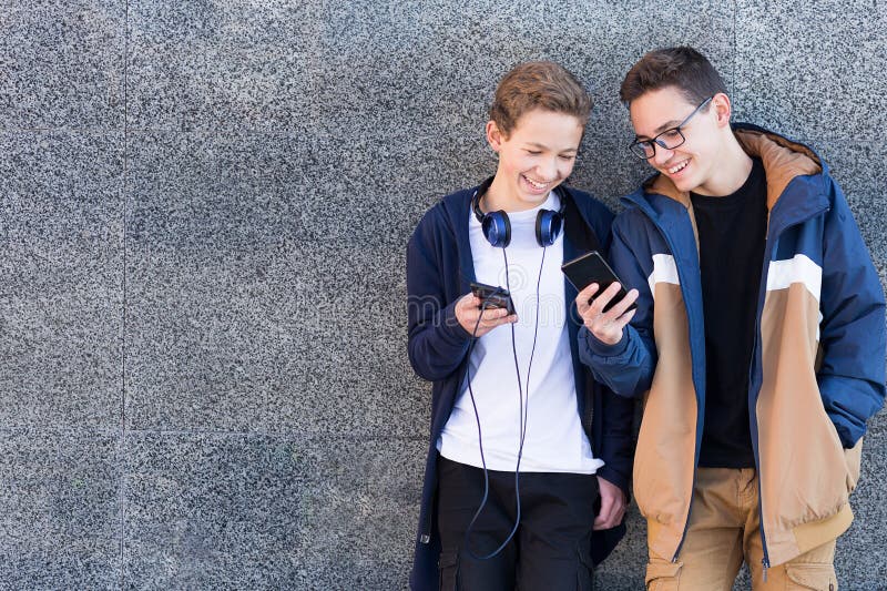 Deux amis se tenant ensemble près du mur regardant dehors le téléphone portable Copiez l'espace images stock Deux amis se tenant ensemble près du mur regardant dehors le téléphone portable Copiez l'espace images stock