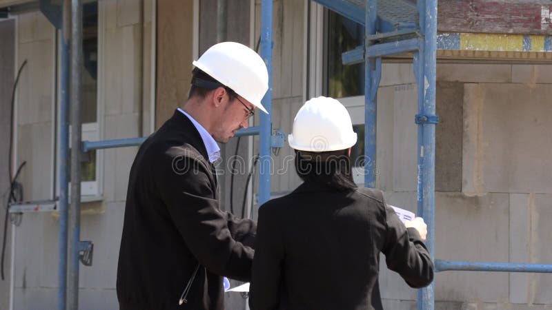 Deux architectes un homme et une femme dans la construction dans les casques blancs