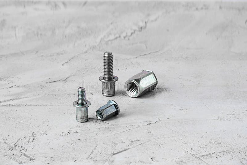 Deux attaches de rivet de bruit en métal de taille différente, sur le fond gris de ciment Horizontal avec l'espace de copie pour photographie stock libre de droits Deux attaches de rivet de bruit en métal de taille différente, sur le fond gris de ciment Horizontal avec l'espace de copie pour photographie stock libre de droits