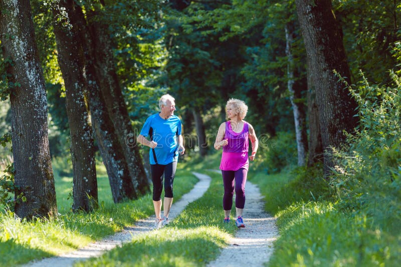 Deux aînés actifs avec un mode de vie sain souriant tandis que joggin