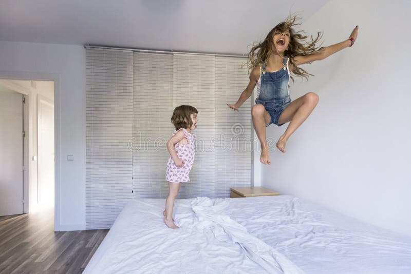 Deux beaux enfants de soeur jouant et sautant sur le lit à la maison Amusement à l'intérieur Amour et mode de vie de famille photographie stock libre de droits Deux beaux enfants de soeur jouant et sautant sur le lit à la maison Amusement à l'intérieur Amour et mode de vie de famille photographie stock libre de droits