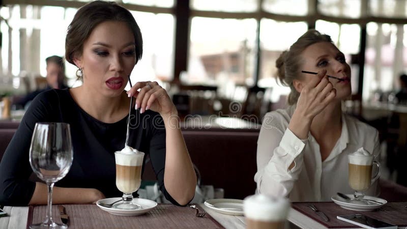 Deux belles femmes dans un café latte potable banque de vidéos