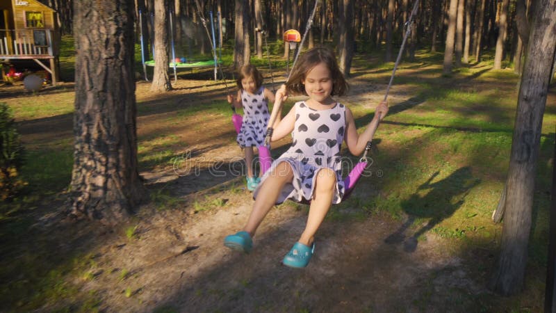 Deux belles filles balancent sur une oscillation dans la forêt