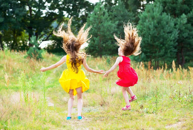 Deux belles petites filles sautant et dansant à l'été ensoleillé d photographie stock libre de droits Deux belles petites filles sautant et dansant à l'été ensoleillé d photographie stock libre de droits