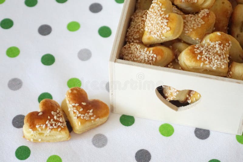 Deux biscuits en forme de coeur avec le sésame sur la serviette de cuisine avec des points et des boîtes en bois décoratives plei images stock Deux biscuits en forme de coeur avec le sésame sur la serviette de cuisine avec des points et des boîtes en bois décoratives plei images stock