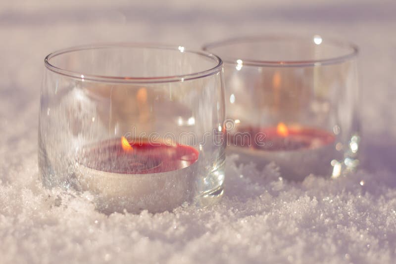 Deux bougies dans les verres sur la neige images stock Deux bougies dans les verres sur la neige images stock