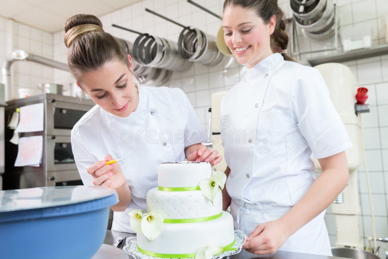 Deux boulangers de pâtisserie décorant le grand gâteau images libres de droits Deux boulangers de pâtisserie décorant le grand gâteau images libres de droits