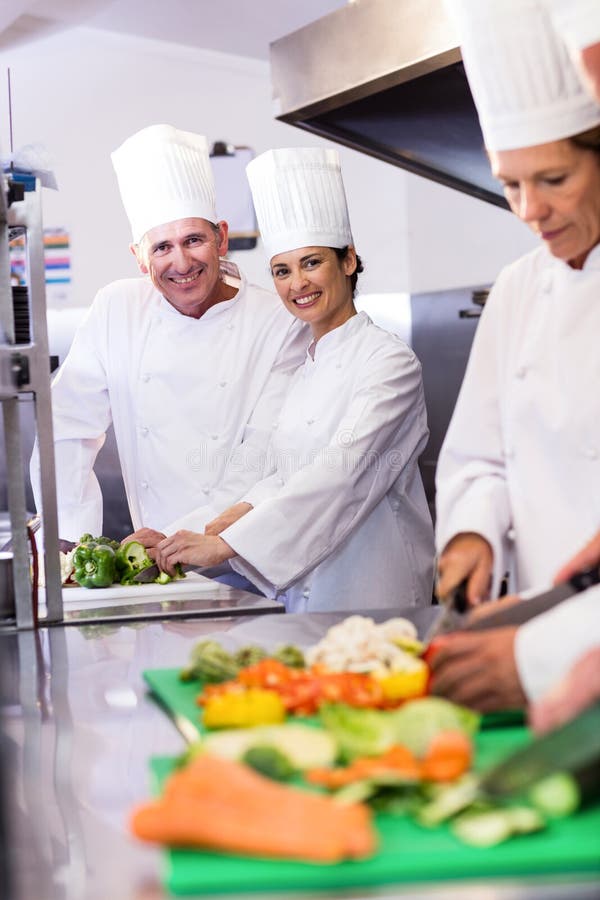 Deux chefs souriant à l'appareil-photo tout en coupant des légumes images libres de droits Deux chefs souriant à l'appareil-photo tout en coupant des légumes images libres de droits